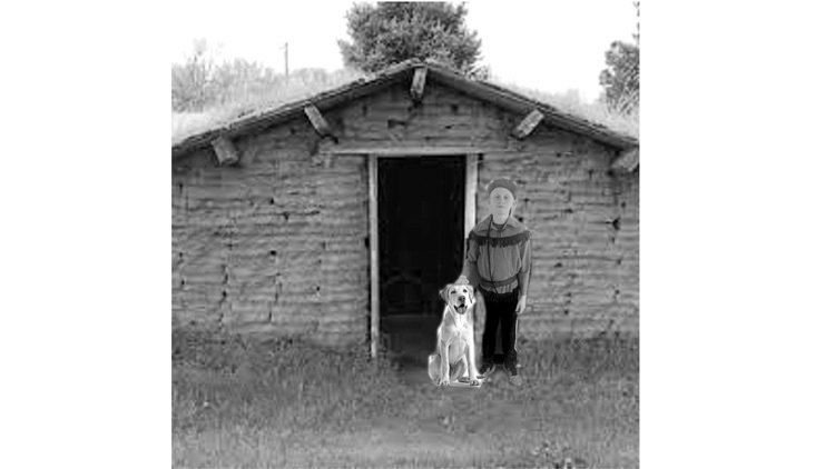 Sawyer and his dog are in front of a sod house  